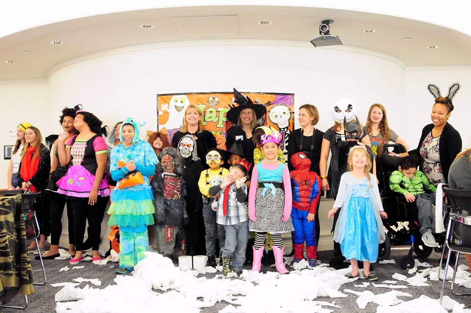 Group of children and adults in colorful costumes indoors.