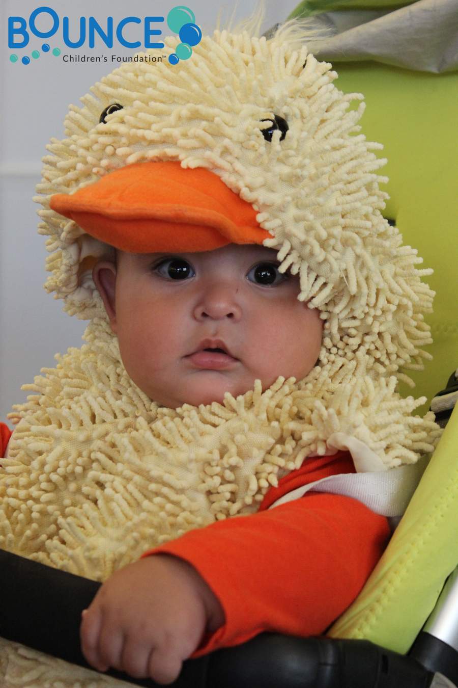 Baby dressed in a fluffy duck costume with an orange beak hat.
